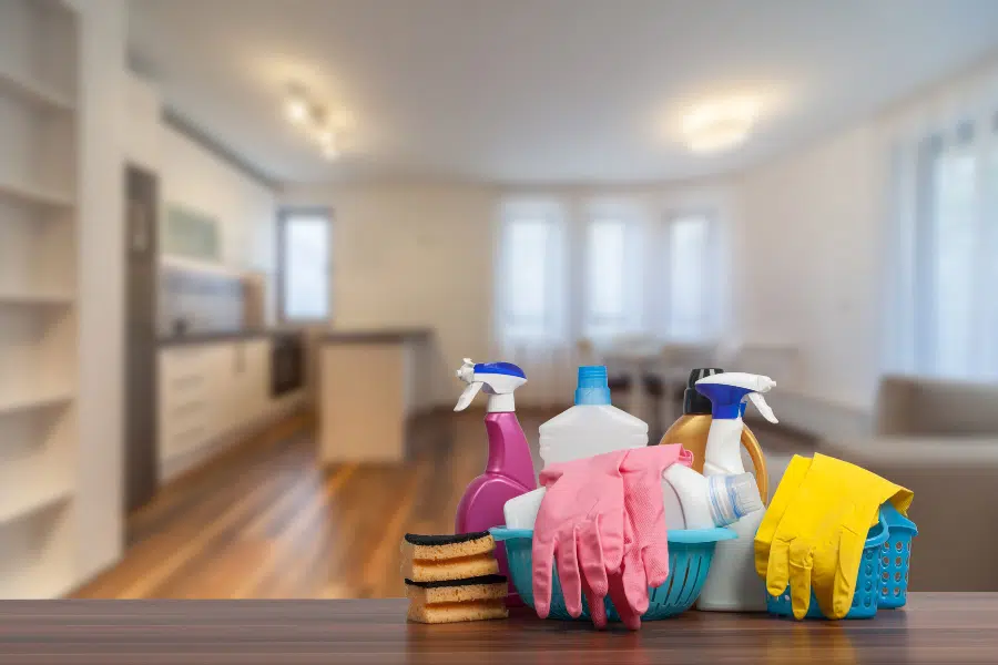 Cleaning sprays, sponges and rubber gloves in a basket in a home